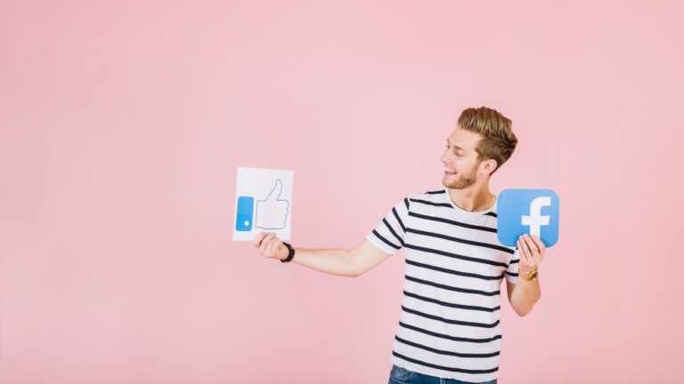 smiling young man holding like facebook icon